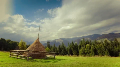 Time lapse clouds moving over beautiful mountain landscape with hay stack  Stock Footage 54922729