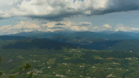 Time-lapse of clouds moving over green patchwork field and mountain ranges Stock Footage 109293887