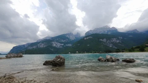 Time-lapse of clouds moving over the rocky mountains and lake coast Stock Footage 109294616