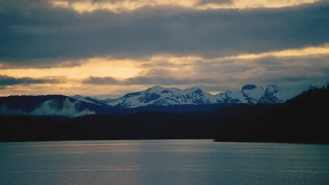 Time-lapse of clouds moving over snowy mountains and a lake at sunset Stock Footage 113261928