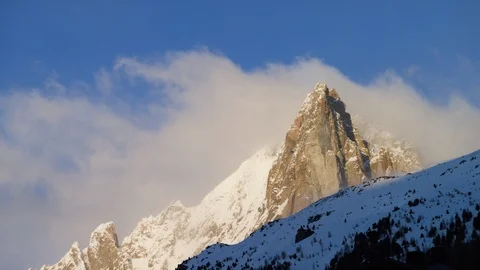 Time-lapse of clouds moving over the snow covered mountain at sunset Stock Footage 116789331