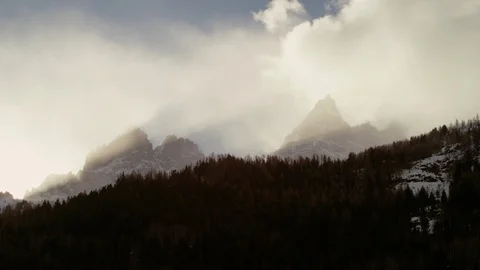 Time-lapse of clouds moving over the snowy mountain covered with forest trees Stock Footage 116789388