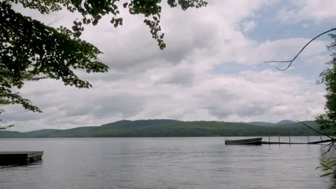 Time lapse of clouds moving quickly away over a lake with boat and dock Stock Footage 83927781