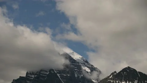 Time lapse of the clouds moving slowly over a group of triangle shaped mountains Stock Footage 135984880