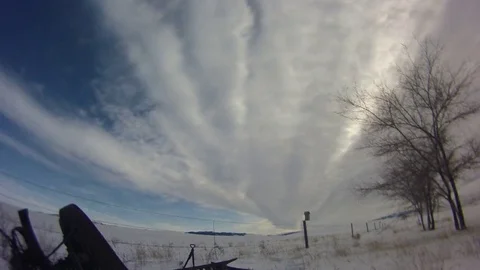 Time-lapse of clouds moving through sky over snow covered field Stock Footage 73051345