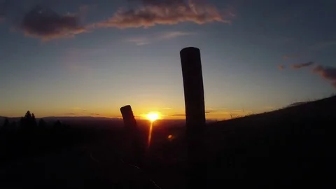 Time-lapse of clouds moving through sky at dusk into night behind fence Stock Footage 73051589