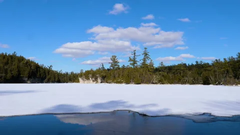 Time Lapse Clouds Over Frozen Snow Covered Lake By Shadows And Lite Pine Trees Video stock 162199814