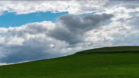 Time-lapse of the clouds over the hill. Dark clouds fly over the green field. Stock Footage 159819992