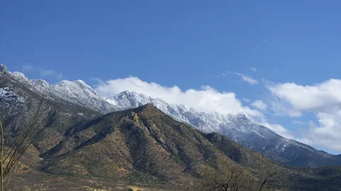 Time lapse of clouds over scenic desert mountains capped with snow Stock Footage 233938395