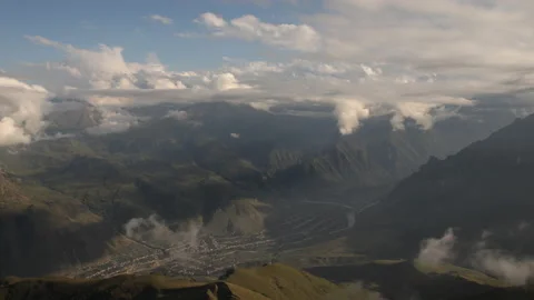 Time lapse of clouds over a village located in a mountain gorge. Stock Footage 97251552