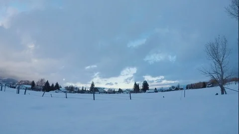 Time-lapse of clouds passing above snow covered village at dusk Stock Footage 116744895