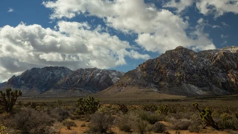 Time Lapse of Clouds Passing Over Lightly Covered Snowy Mountains Video stock 107946620