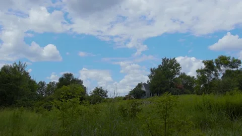 Time lapse of clouds passing over a beautiful meadow with a small house. Stock Footage 158203823