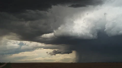 Time-lapse clouds of a prairie storm move to the right, dragging a curtain of Stock Footage