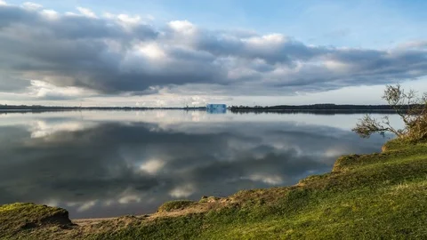 Time lapse of clouds reflecting in the ocean captured on a green peninsula Video stock 126164517
