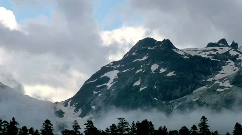 Time lapse of clouds rising from snowy high mountains and forests in sunset 스톡 동영상 65992687