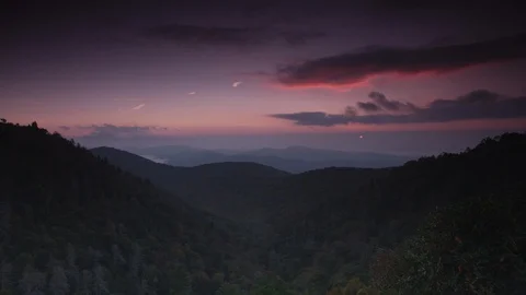 Time-lapse of clouds rolling over the forest covered mountains at sunrise Stock Footage 103398764