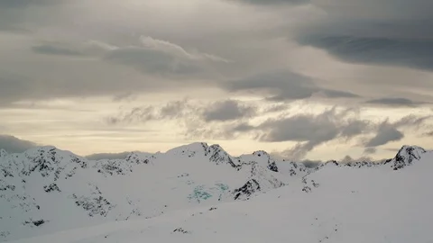 Time-lapse of clouds rolling over snow covered mountain ranges at sunset Stock Footage 113249784