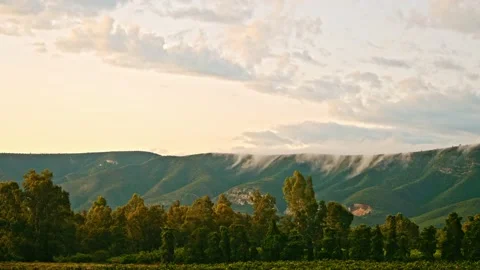 Time-lapse of clouds rolling over mountain range over rural landscape Stock Footage 235894652