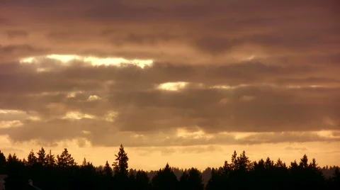 Time lapse of clouds rolling by at sunrise with rays of light. Video stock 384343