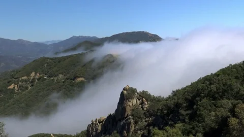 Time Lapse of Clouds Spilling Over Mountain Ridge Stock Footage 74750751