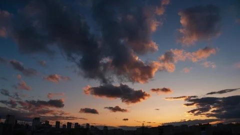 Time lapse clouds at sunset over city skyline silhouette. 4K. Stock Footage 253413756