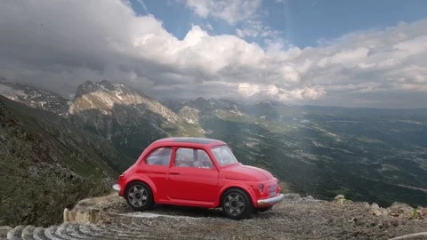 Time lapse of the cloudy sky in the mountains with a red car in colse up Vidéo 96000893