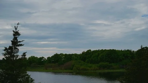 Time lapse of cloudy sky racing across a lake a trees Stock Footage 122389922