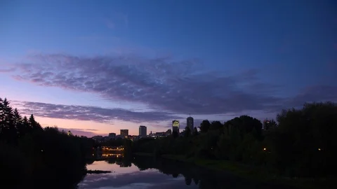 Time lapse of colorful clouds moving over city, mirroring on quiet river. Stock Footage 118303425