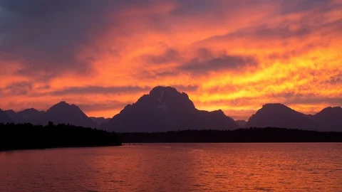 Time lapse of colorful sunset clouds above the Grand Teton mountains and a lake Stock Footage 95053298