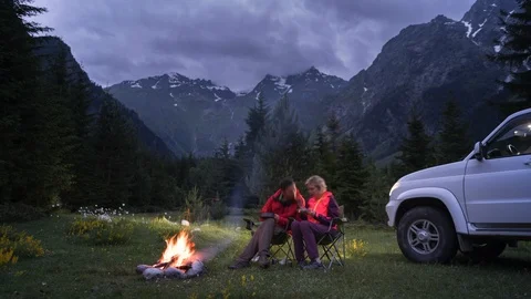 Time-lapse of couple chatting by bonfire in camping in mountain valley. sunset Video stock 113994080