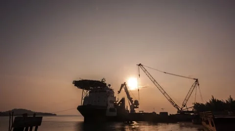 Time-lapse of Cranes Loading And Unloading Cargo From Ship At Port At Sunset Stock Footage 48438158