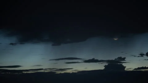Time lapse of the crescent moon rising into rain clouds Video stock 250187922