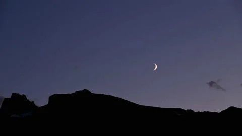 Time lapse of a crescent moon slowly moving through purple colored evening sky Stock Footage 139691295