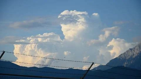 Time lapse of Cumulonimbus clouds forming behind barbed wire fence Stock Footage 214415301