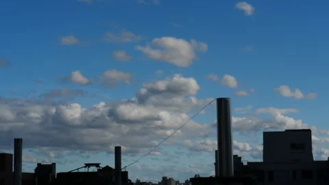Time lapse of cumulus clouds moving over the tops of buildings 動画素材 136716741