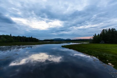 Time-lapse of dark clouds floating over the river and landscape at sunset Stock Footage 104502114