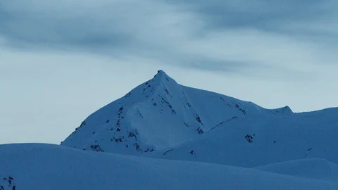 Time-lapse of dark clouds moving over snowy mountains at dusk Stock Footage 113254592