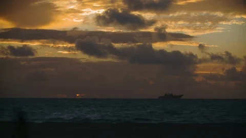Time-lapse of dark clouds moving over ocean during sunrise Stock Footage 117734352