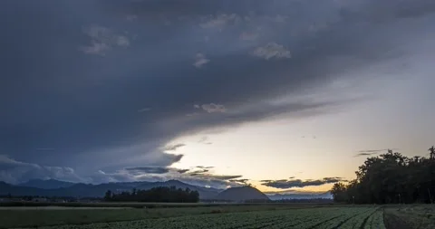 Time lapse of dark clouds moving over farming field and hills Stock Footage 138746832