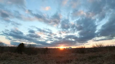 Time lapse of dark clouds moving over dry grass at sunset Stock Footage 153496653