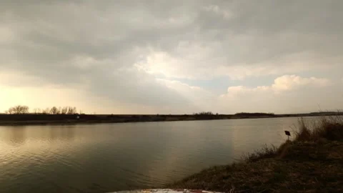 Time lapse of of dark clouds revealing blue sky above flowing river in spring Stock Footage 263148942