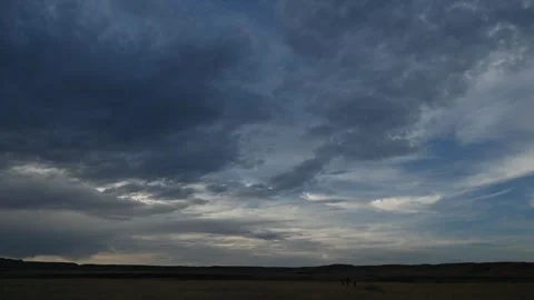 Time lapse of dark late day clouds moving above a barren prairie landscape Stock Footage 312076568