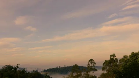 Time lapse of a dissipating fog below colorful slow clouds moving at dawn ove Stock Footage 314527370
