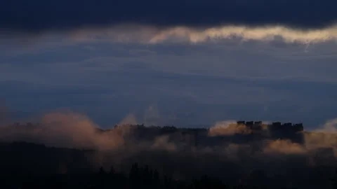 Time lapse of dramatic clouds and fog rolling over an urban skyline at sunrise, Stock Footage 337149708