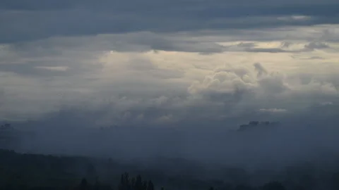 Time lapse of dramatic clouds and fog rolling over an urban skyline at sunrise, Stock Footage 337150231