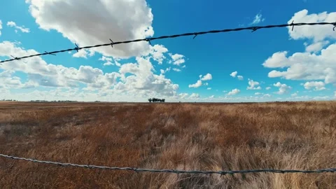 Time-Lapse: Dramatic Clouds Moving Over Barbed Wire Fence and Distant Trees in a Stock Footage 318335319