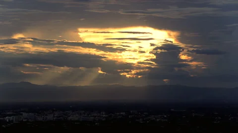 Time Lapse of Dramatic golden sunset glowing through dark clouds above a mo.. Stock Footage 346467206
