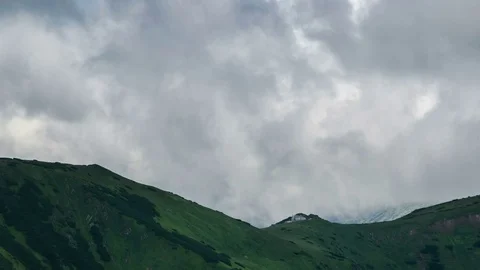 Time lapse of dramatic sky clouds over green mountain meadow chalet zoom out Stock Footage 70495759