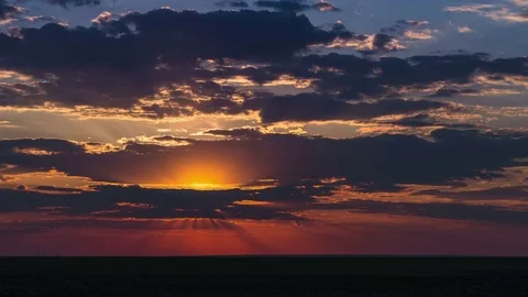Time lapse of dusk with sunset and flowing colorful clouds above the field Video stock 75332605